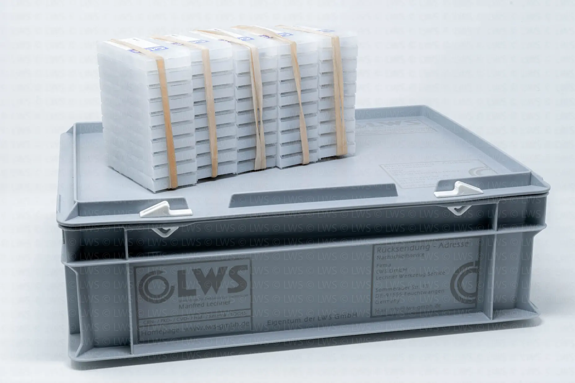 Stapel verpackter Papierstapel auf grauer Kunststoffbox mit LWS-Schriftzug.