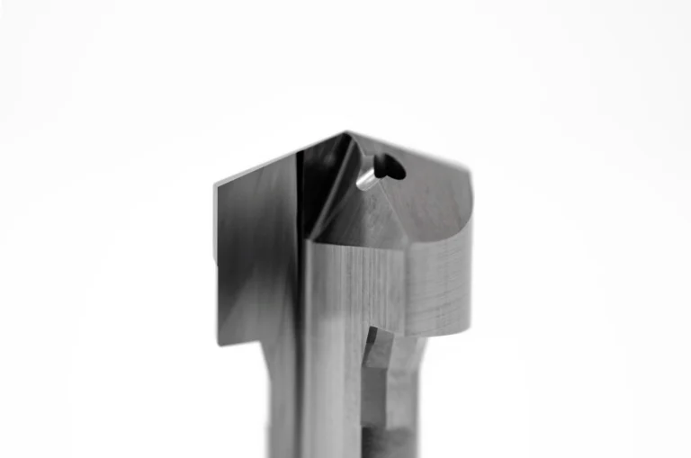 Nahaufnahme eines präzise gearbeiteten Metallteils mit Bohrung, auf weißem Hintergrund.