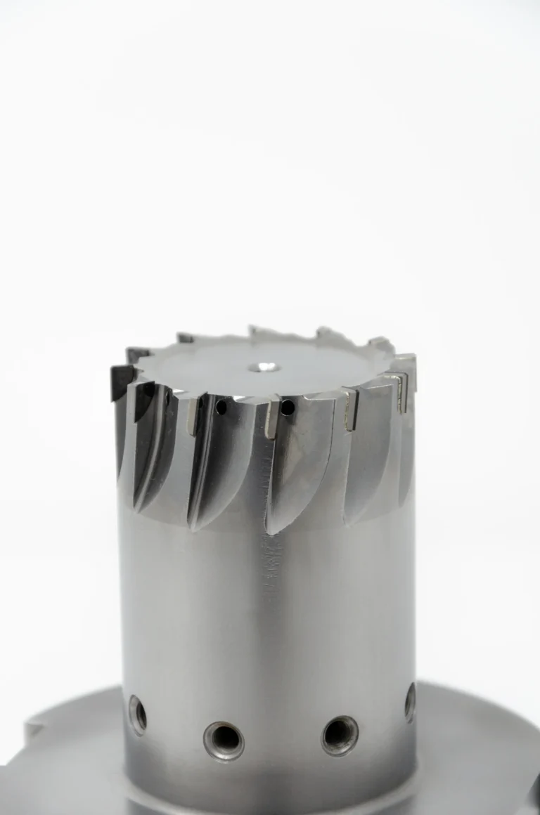 Metallener Bohrkopf mit scharfen Schneiden und Löchern auf hellem Hintergrund.