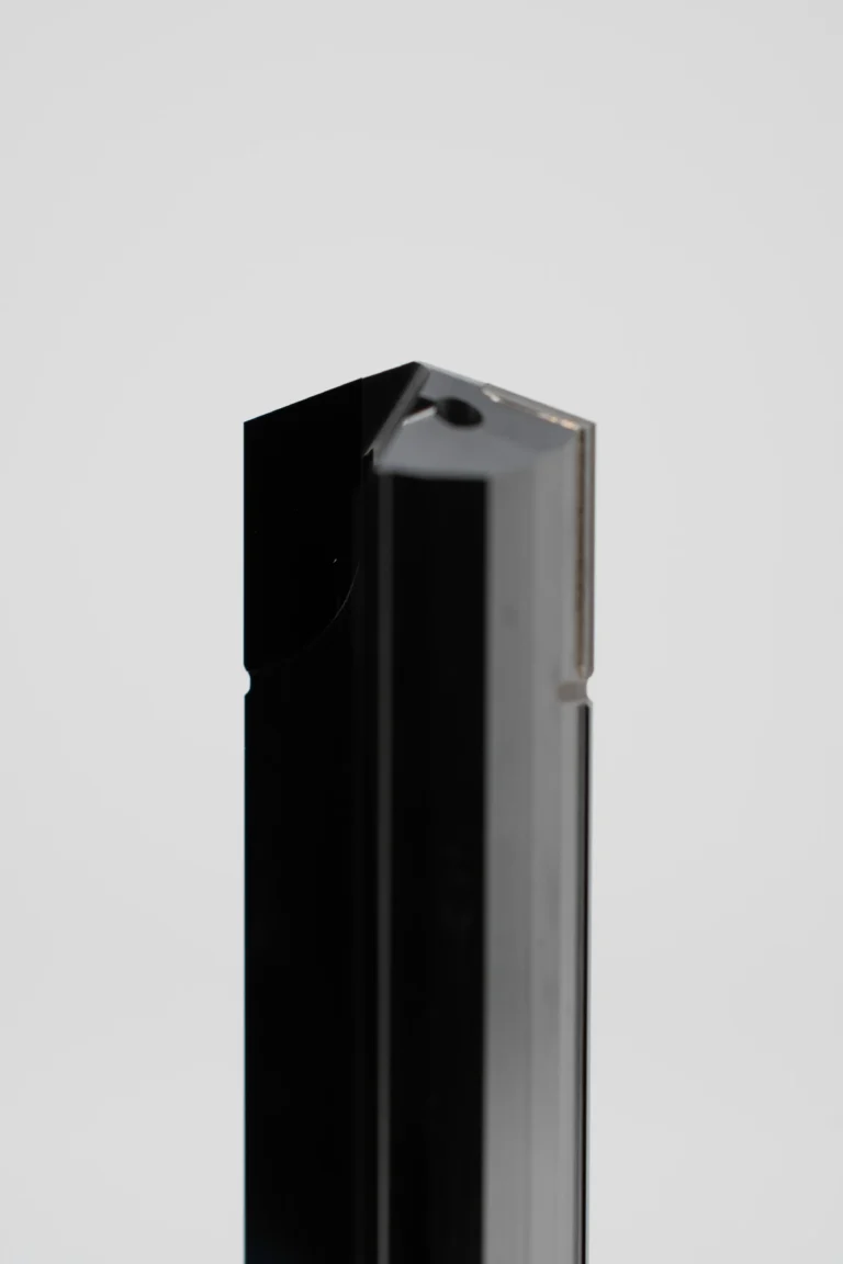 Nahaufnahme eines schwarzen, L-förmigen Aluminiumprofils vor hellem Hintergrund.