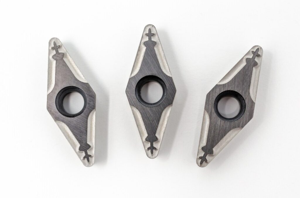 Drei metallene Fahrrad-Scheibenbremsbeläge auf weißem Hintergrund.