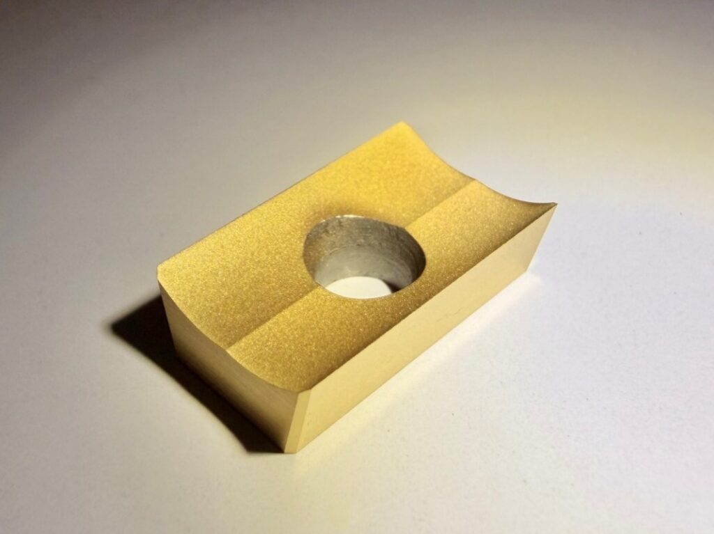 Goldenes Rechteck mit zentraler runder Aussparung auf hellem Untergrund.