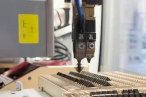 Roboterarm montiert elektronische Komponenten in einer Fabrik.